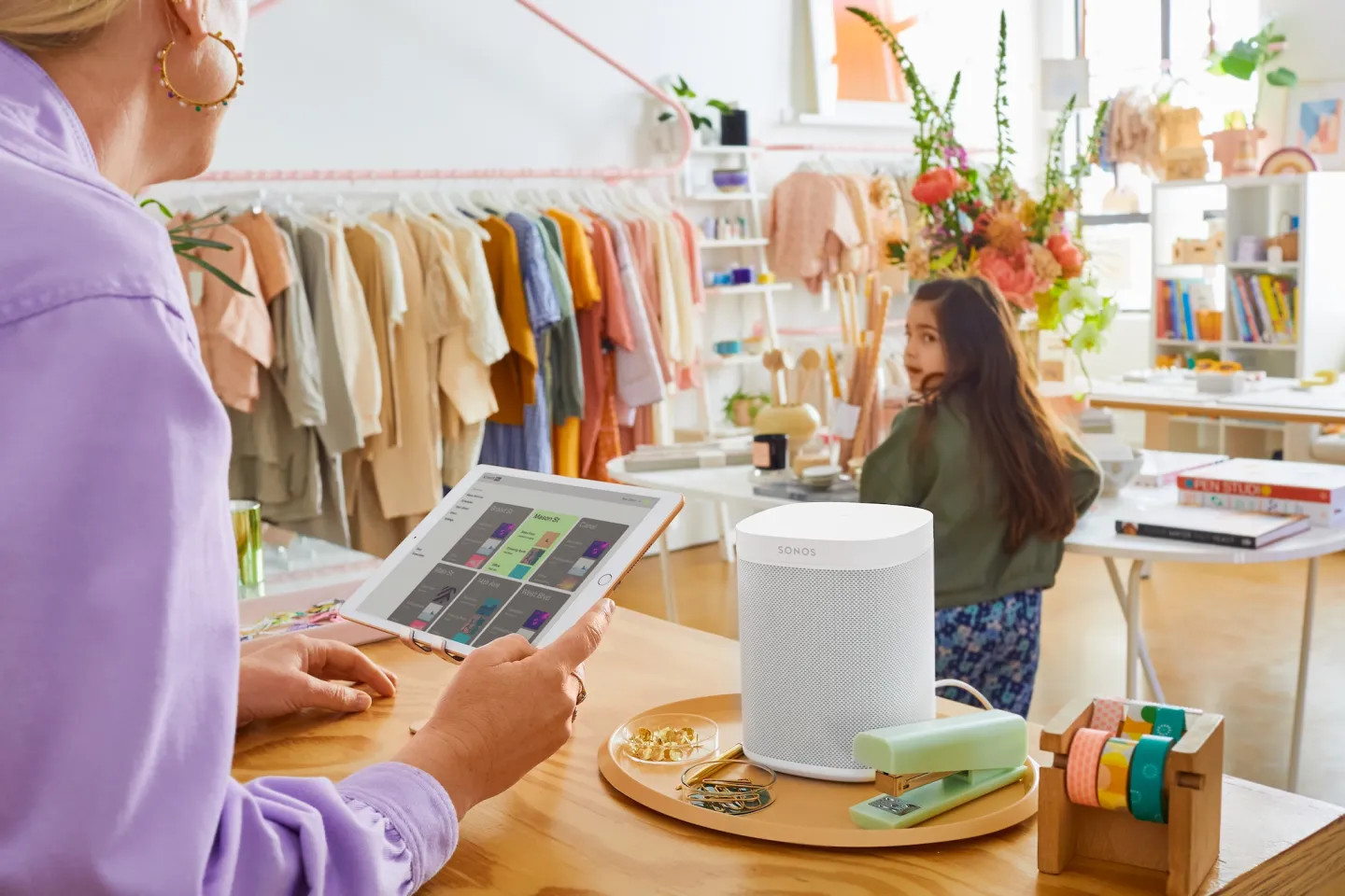 Retail store owner controlling Soundsuit on tablet next to Sonos speaker